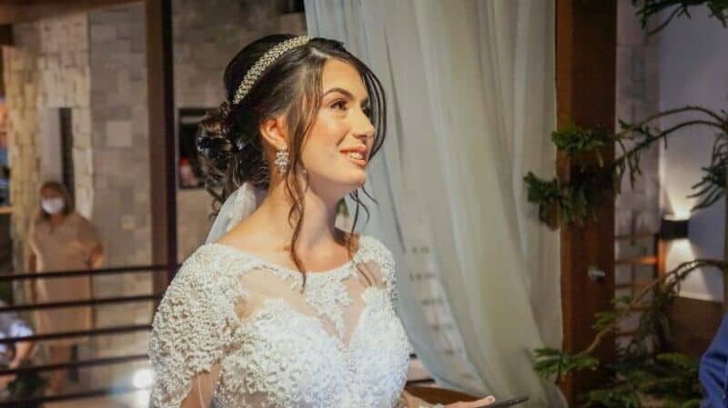 Bride in wedding dress with veil, smiling, in a decorated venue.