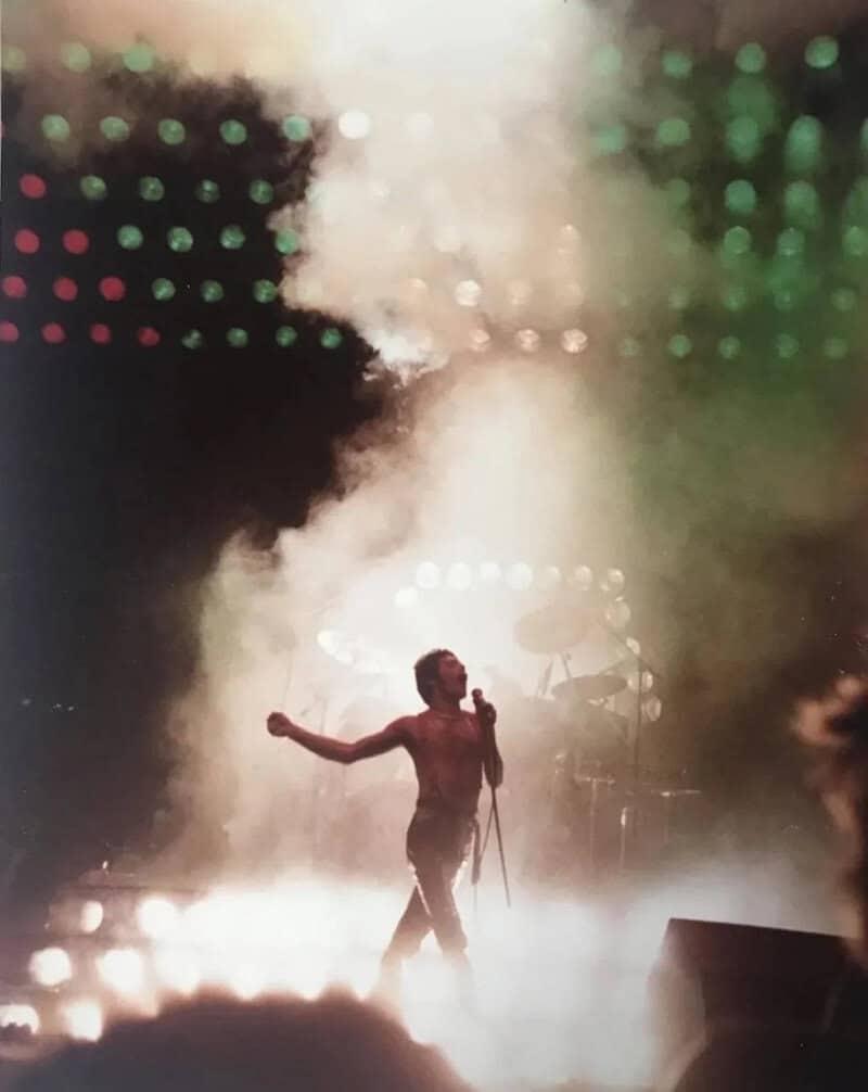 Performer singing on stage with colorful lights and fog effects.