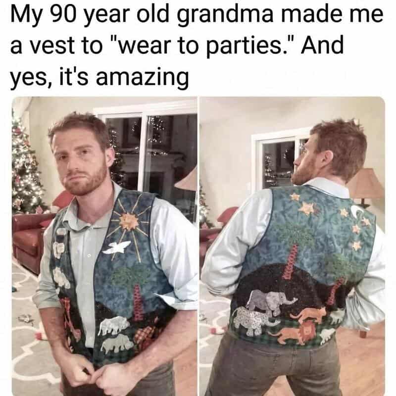 Man wearing a festive vest with animals and Christmas decorations, in a living room.