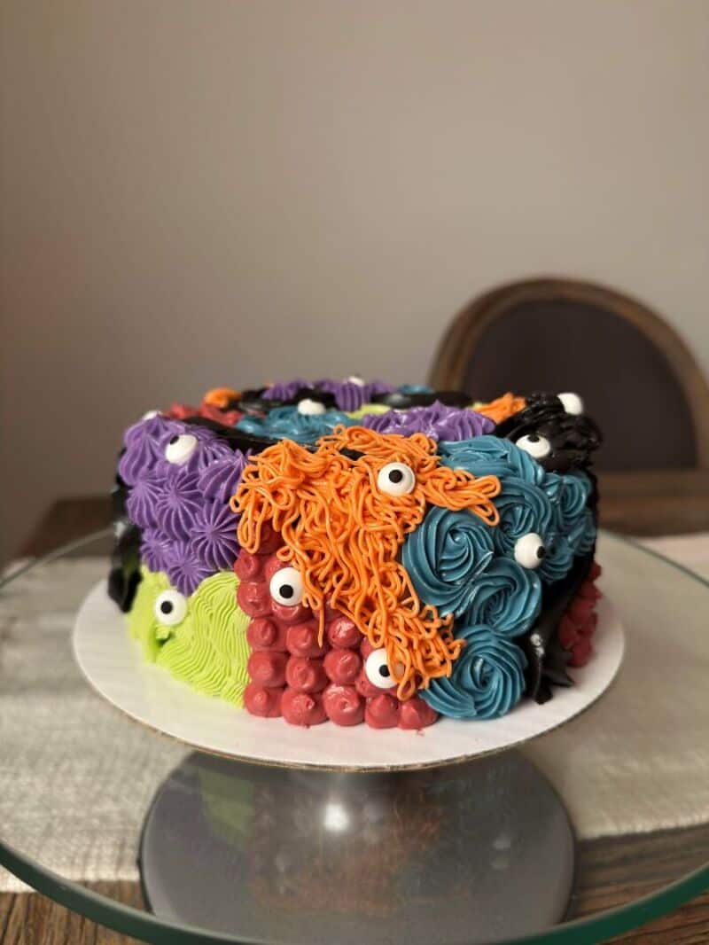 Colorful cake decorated with frosting and candy eyes, resembling a monster.