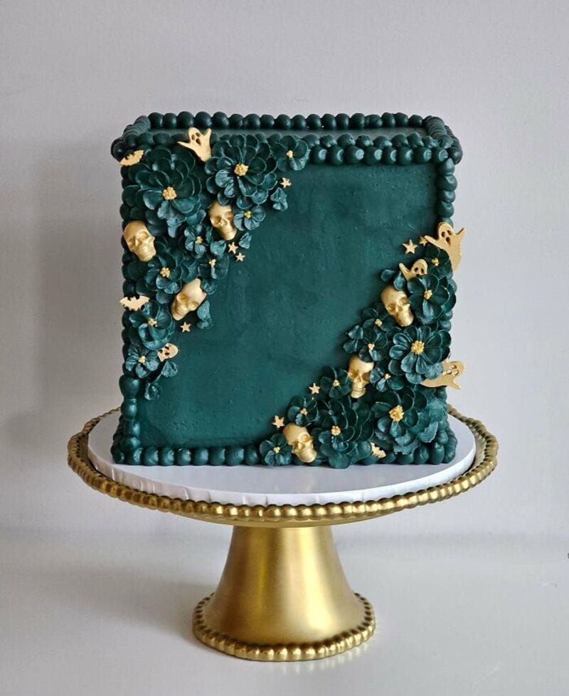 Elegant teal cake with floral and gold accents on a gold stand.