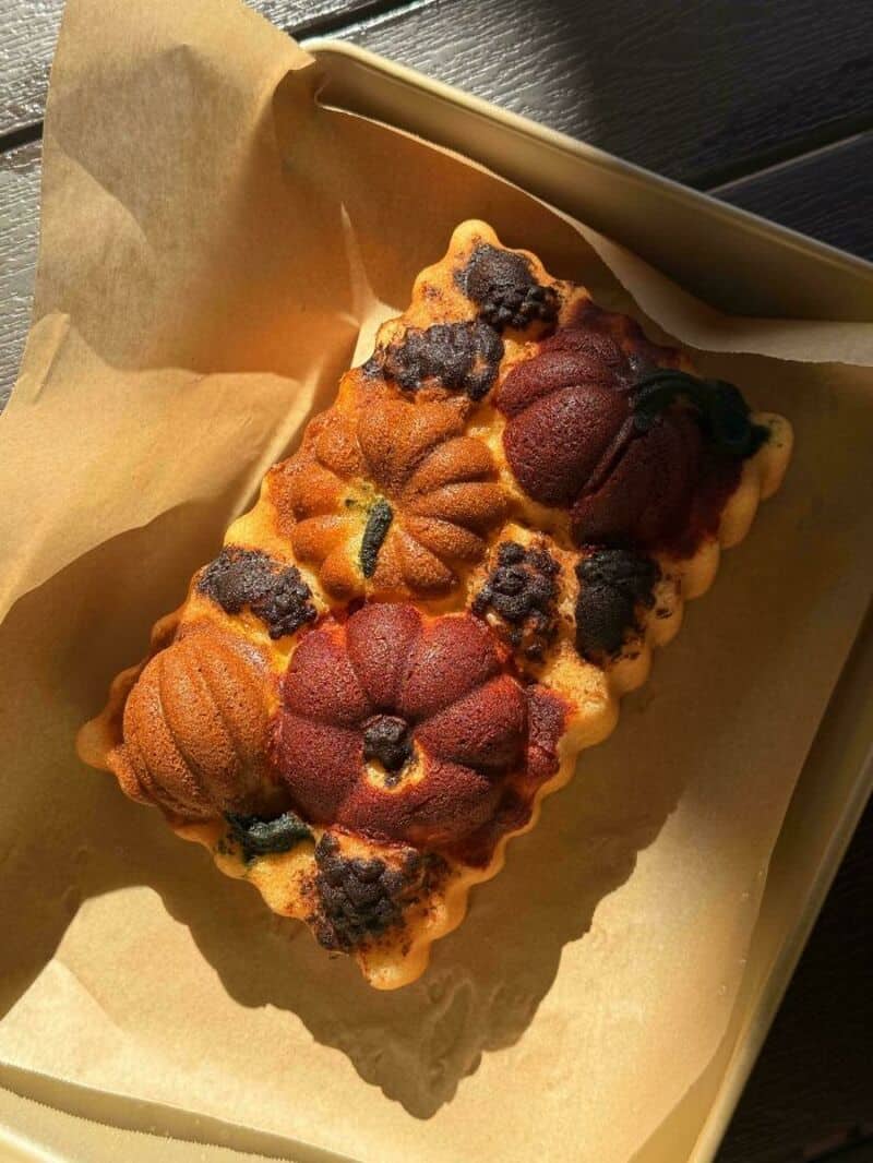 Baked bread with pumpkin and berry shapes on parchment paper in a baking tray.