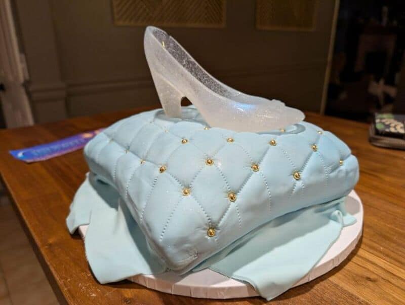 Cake shaped like a blue quilted handbag with a high heel shoe on top.