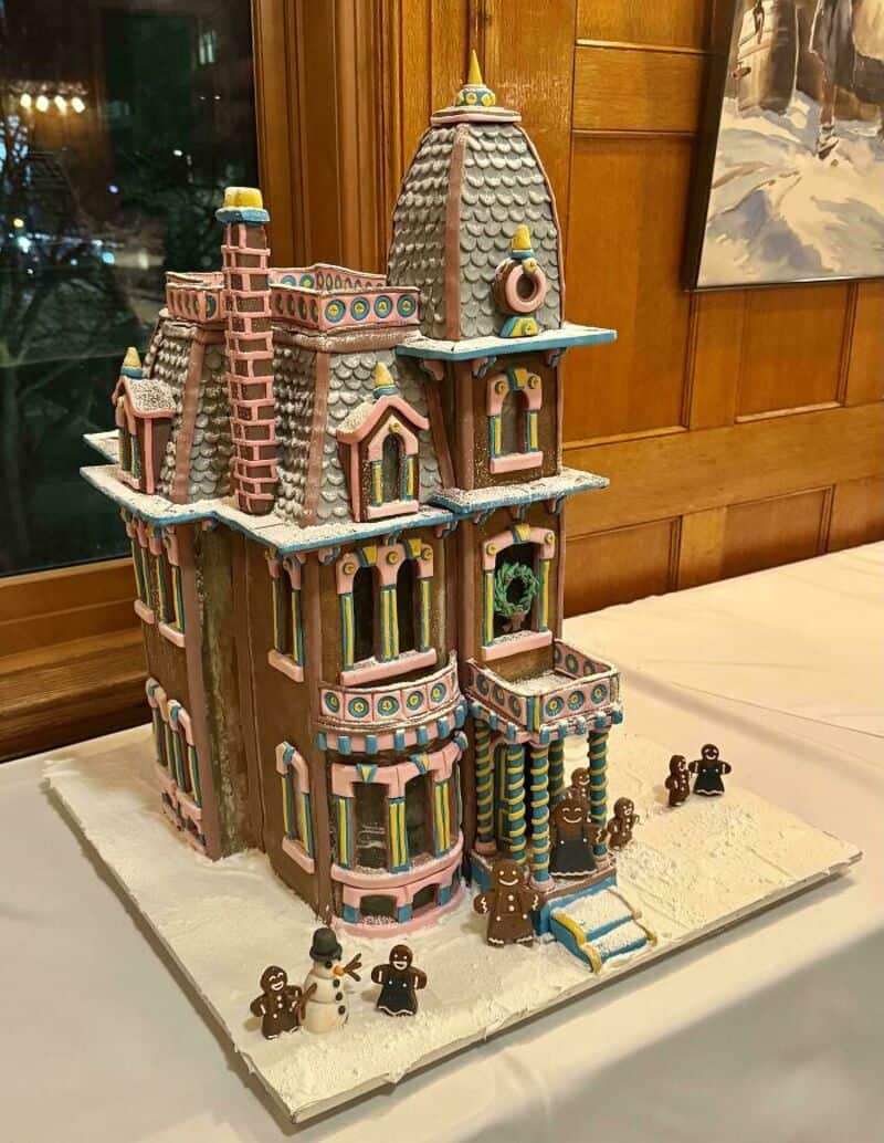 Colorful gingerbread house with gingerbread men on a snowy base.