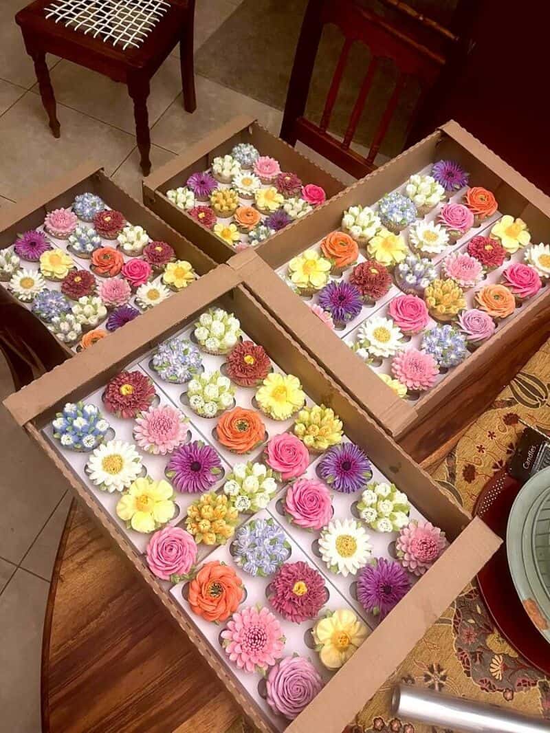 Colorful flower arrangements in cardboard boxes on a wooden table.