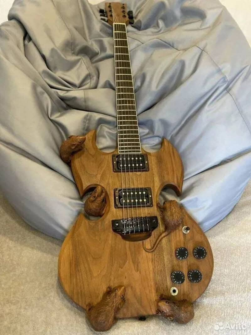 Wooden electric guitar with animal paw-shaped details on a gray bedspread.