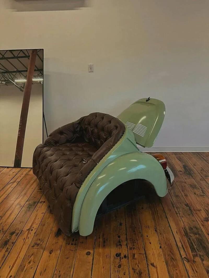 Vintage green pedal car with brown cushioned seat and open hood.