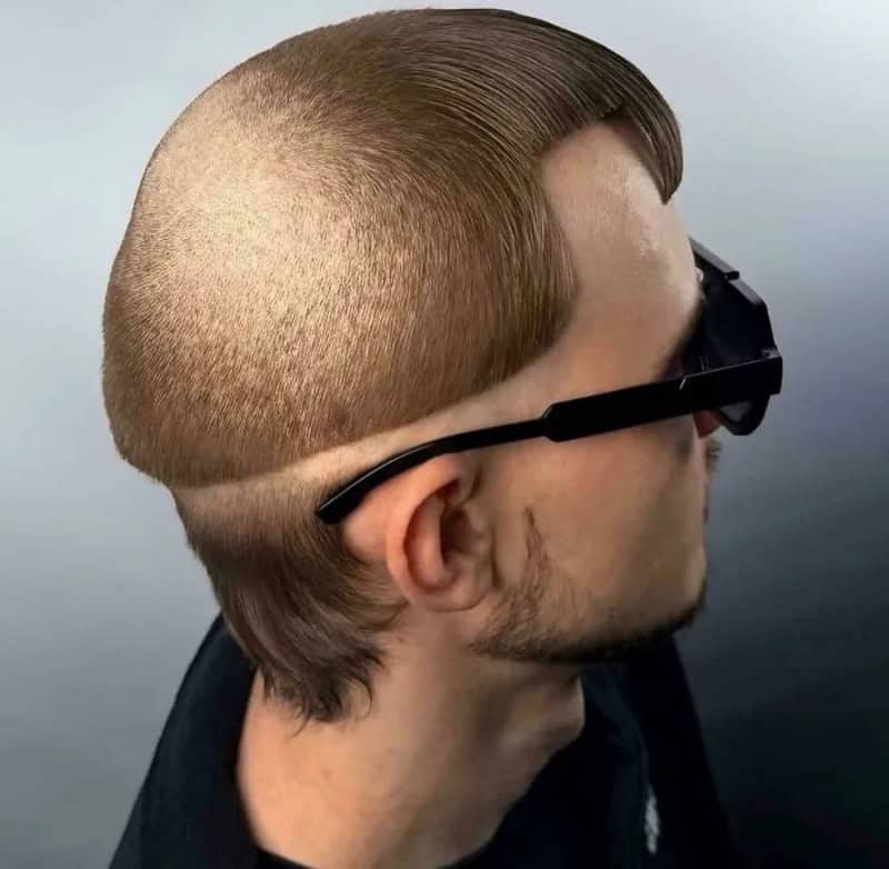 Side view of a man with a unique haircut and sunglasses, with a shaved section and styled hair.