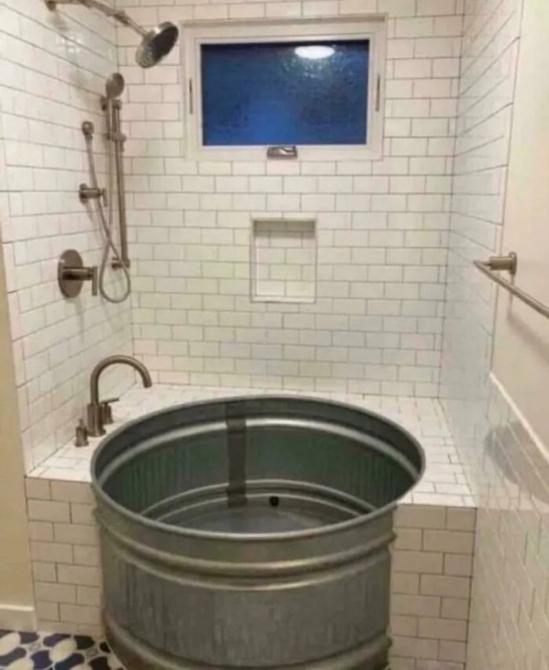 A bathroom with a large metal tub, shower, and a small window.