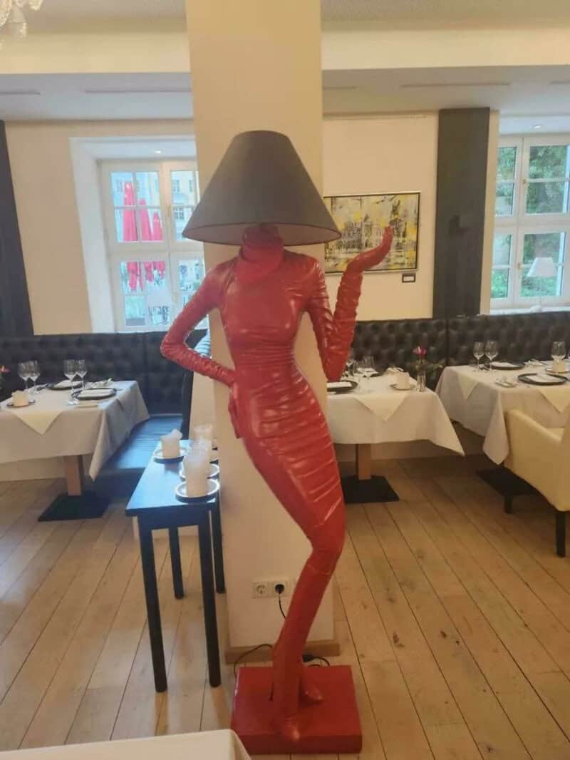 Red sculpture of a woman with a lampshade as a head in a restaurant.