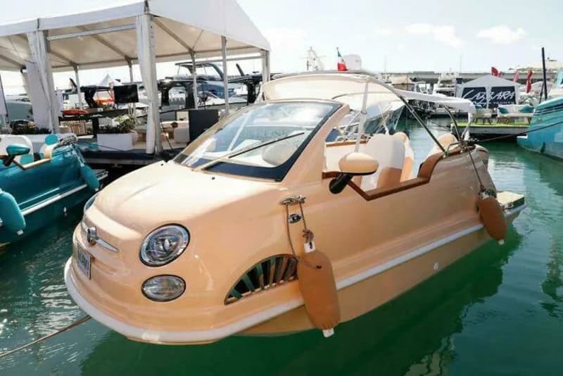 Unique peach-colored boat with a rounded front and large windows docked at marina.