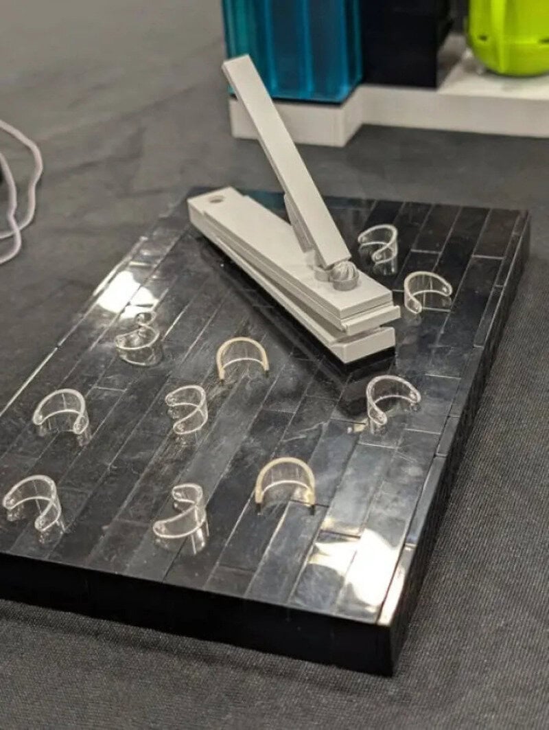 A white stapler on a black marble surface with metal rings around it.