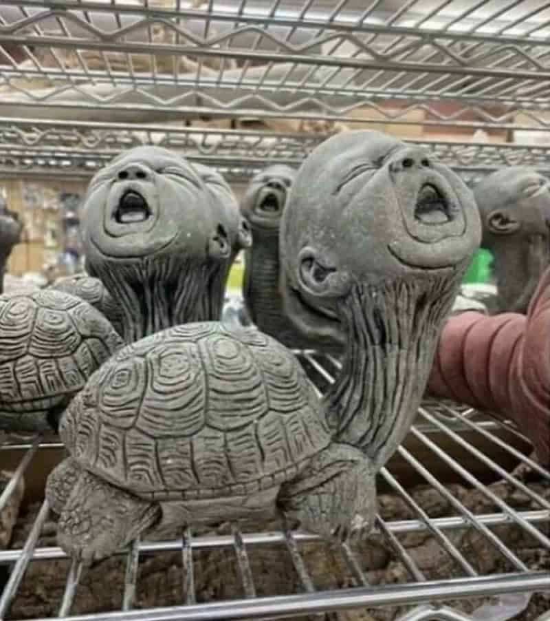 Turtle sculptures with human faces on their heads, displayed on a metal shelf.