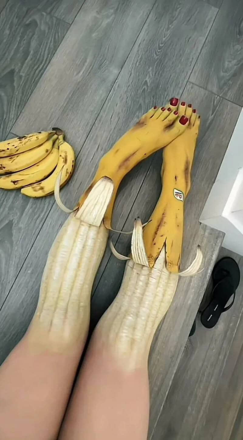 Humorous banana feet with banana peel shoes on a wooden floor.