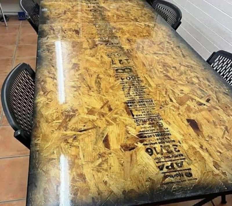 Wooden table with a plastic cover and black chairs around it.
