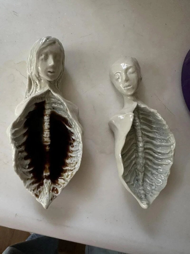 Two ceramic sculptures of human torsos with faces, one with an open chest showing ribs.