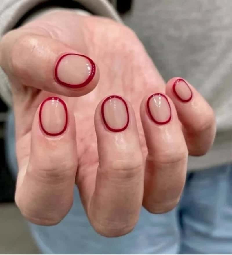Hand with red nail polish and a red ring around each fingernail.