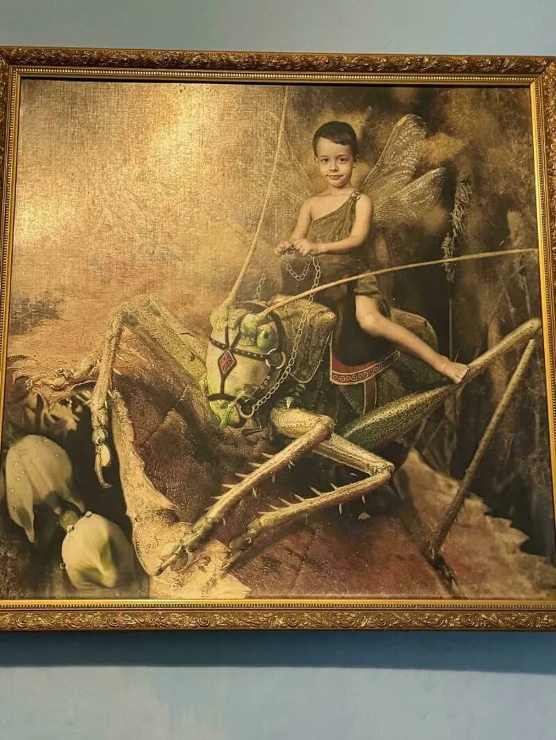Child riding a large, realistic insect sculpture in a museum exhibit.