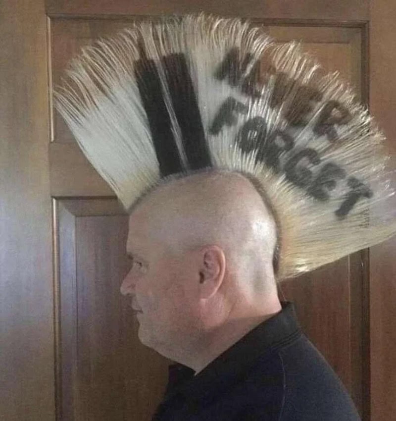 Man with a mohawk hairstyle with 'I Hate Mowing' written in black on the hair.