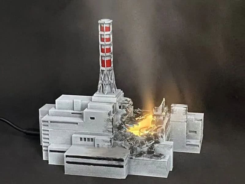 Miniature model of a nuclear power plant with a smoking chimney and fire effects.