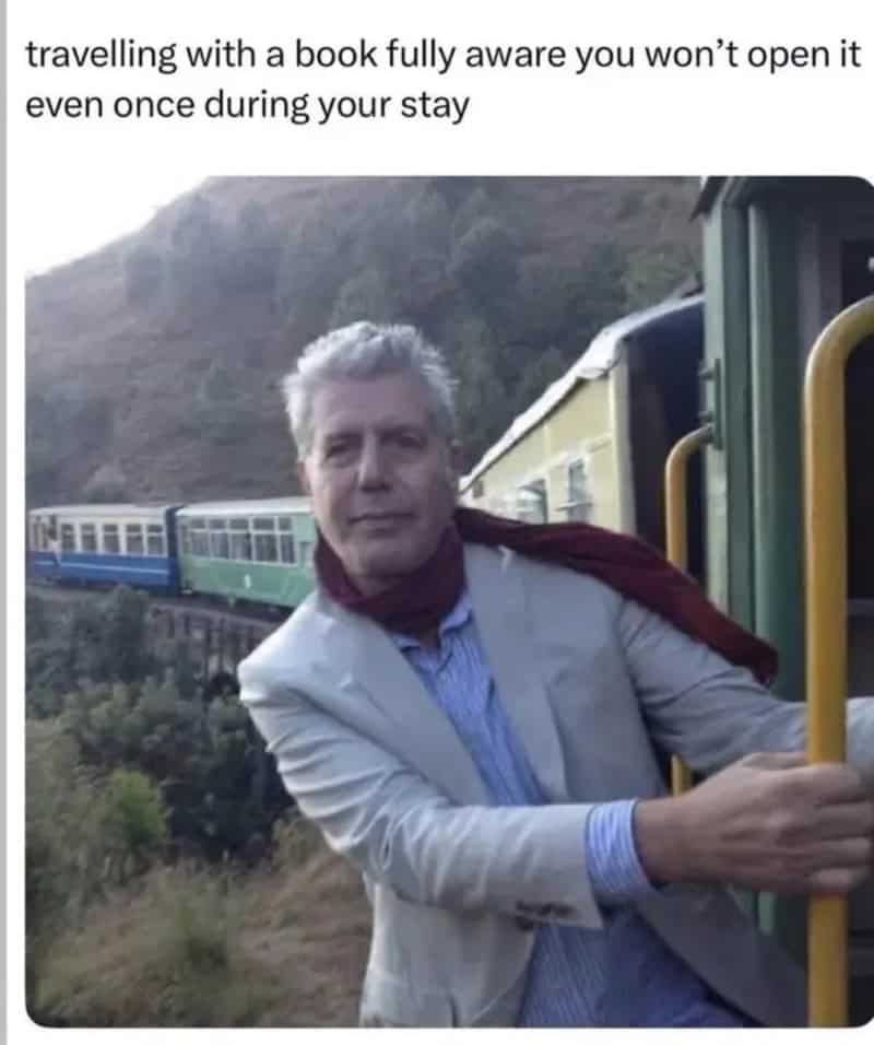 Man with gray hair in a light suit on a train, with a scenic mountain background.