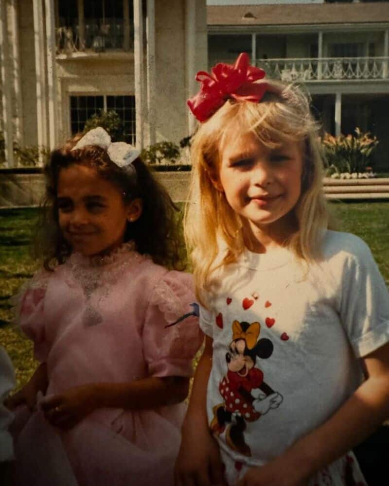 Two young girls outdoors, one in a pink dress and the other in a Minnie Mouse T-shirt.