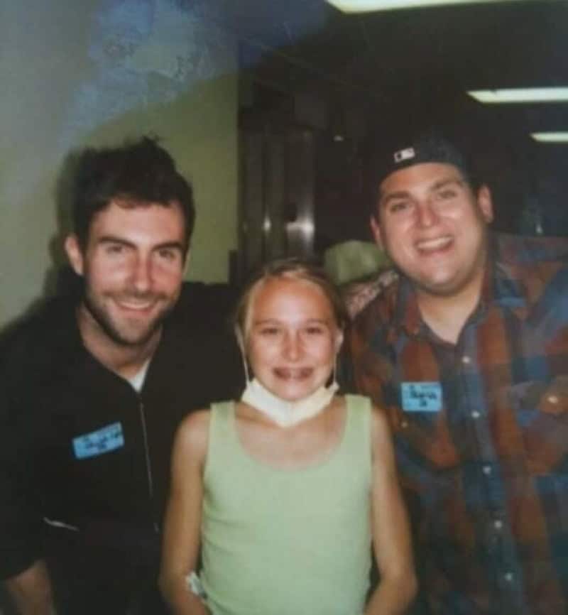 Three people smiling, two men and a girl, in a hospital setting.
