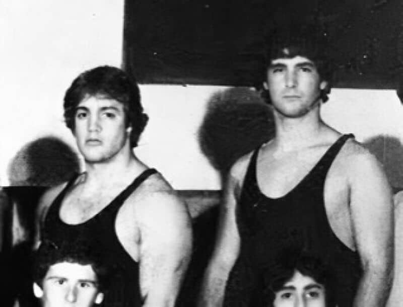 Black and white photo of two young men in tank tops, standing side by side.