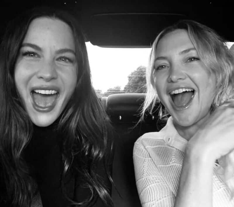 Two women smiling and laughing in a car, black and white photo.