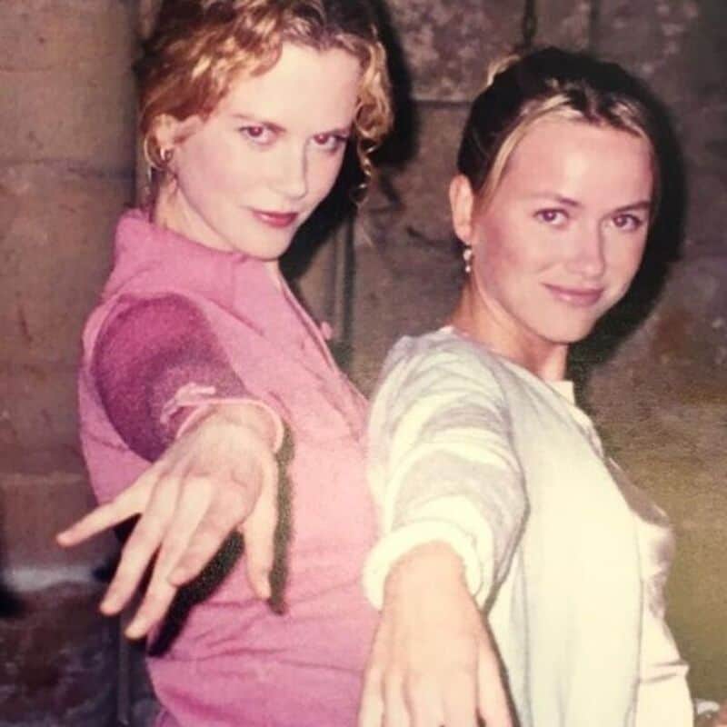 Two women with outstretched arms, one in pink, the other in light green, smiling.
