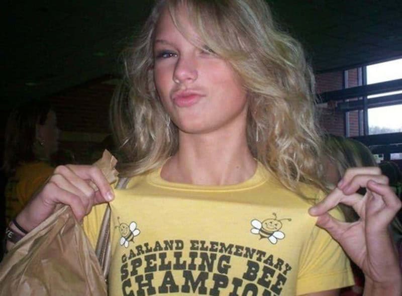 Young girl with wavy blonde hair wearing a yellow T-shirt, making a playful face.