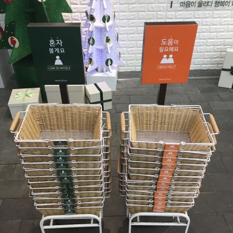 Two shopping carts with signs for self-service and help needed in Korean and English.