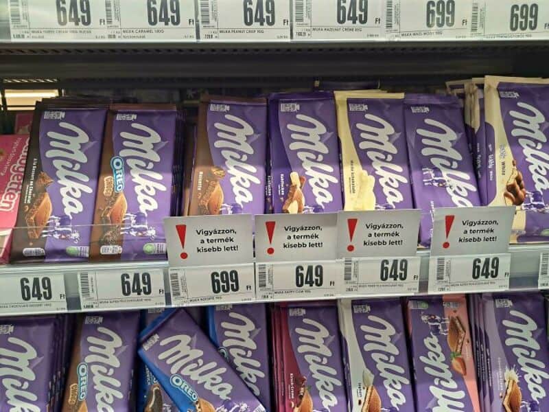 Milka Oreo chocolate bars on store shelf with price tags and warning signs.