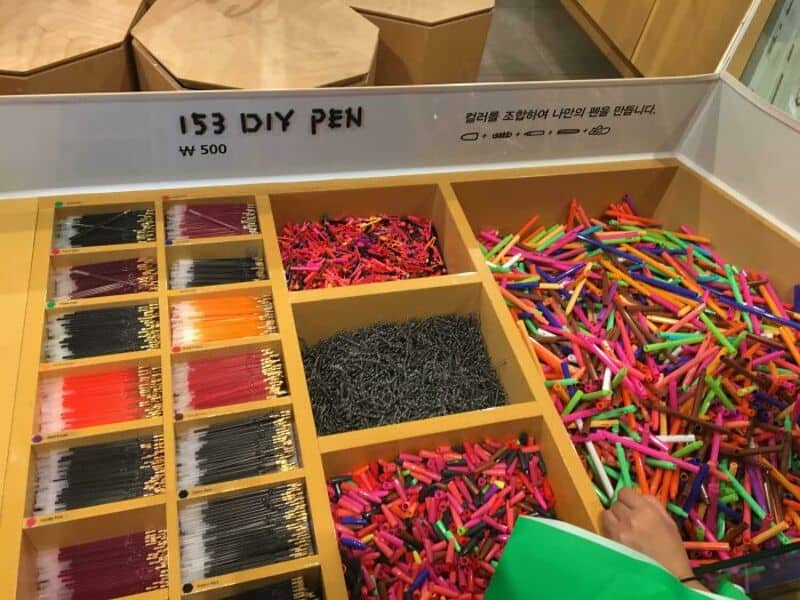 Colorful DIY pens with various colored tips and black ink refills in a display box.