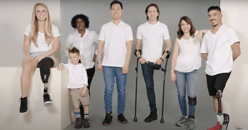Diverse group of people, some with disabilities, smiling together in casual clothing.