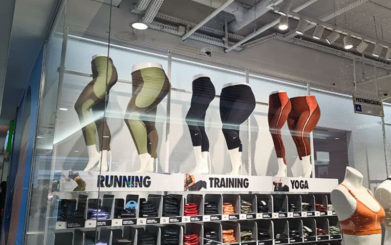 Display of sportswear mannequins with running, training, and yoga apparel in a store window.