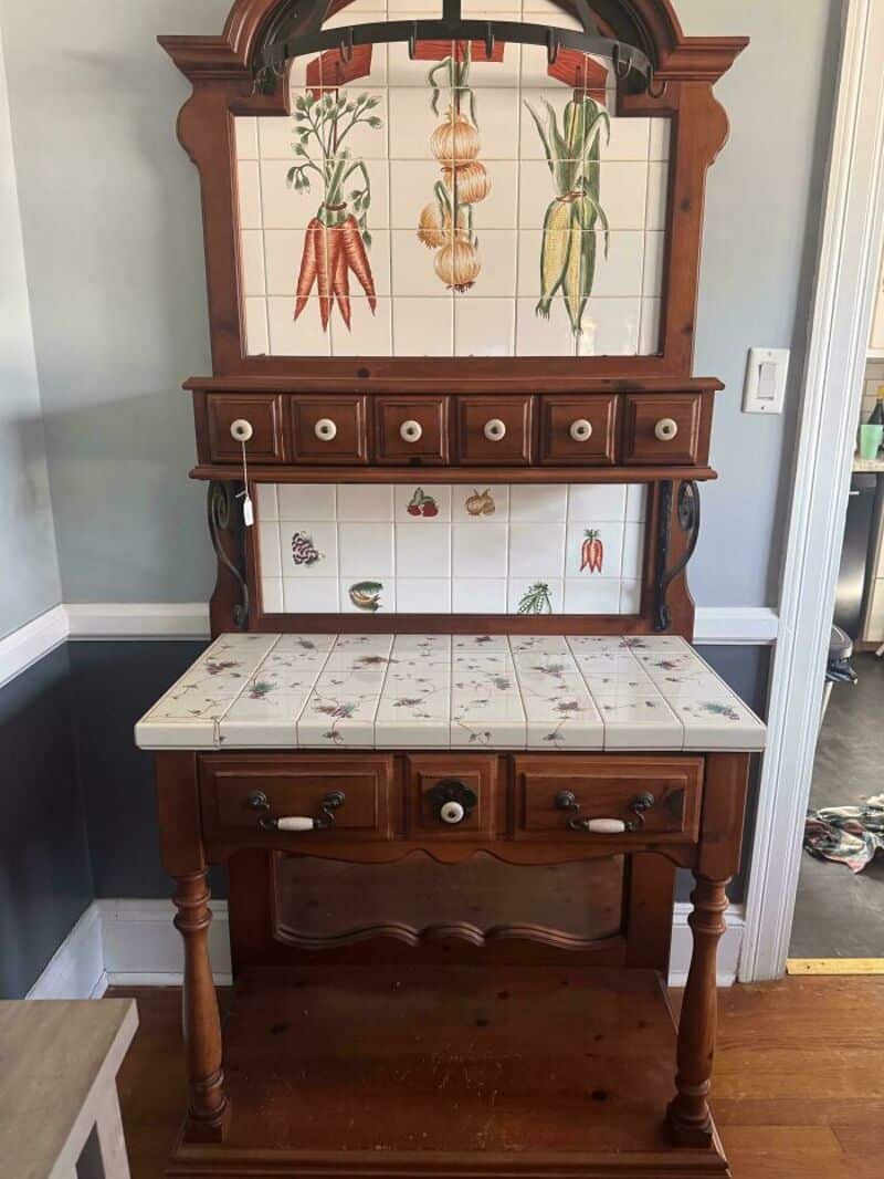 Vintage wooden hall tree with tile panels and botanical illustrations.