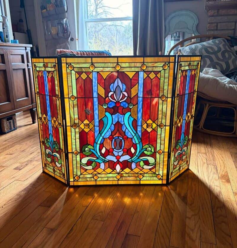 Colorful stained glass room divider with floral and geometric patterns in a living room.