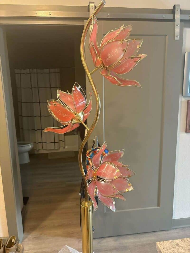 Decorative metal flower sculpture with pink petals and gold accents.