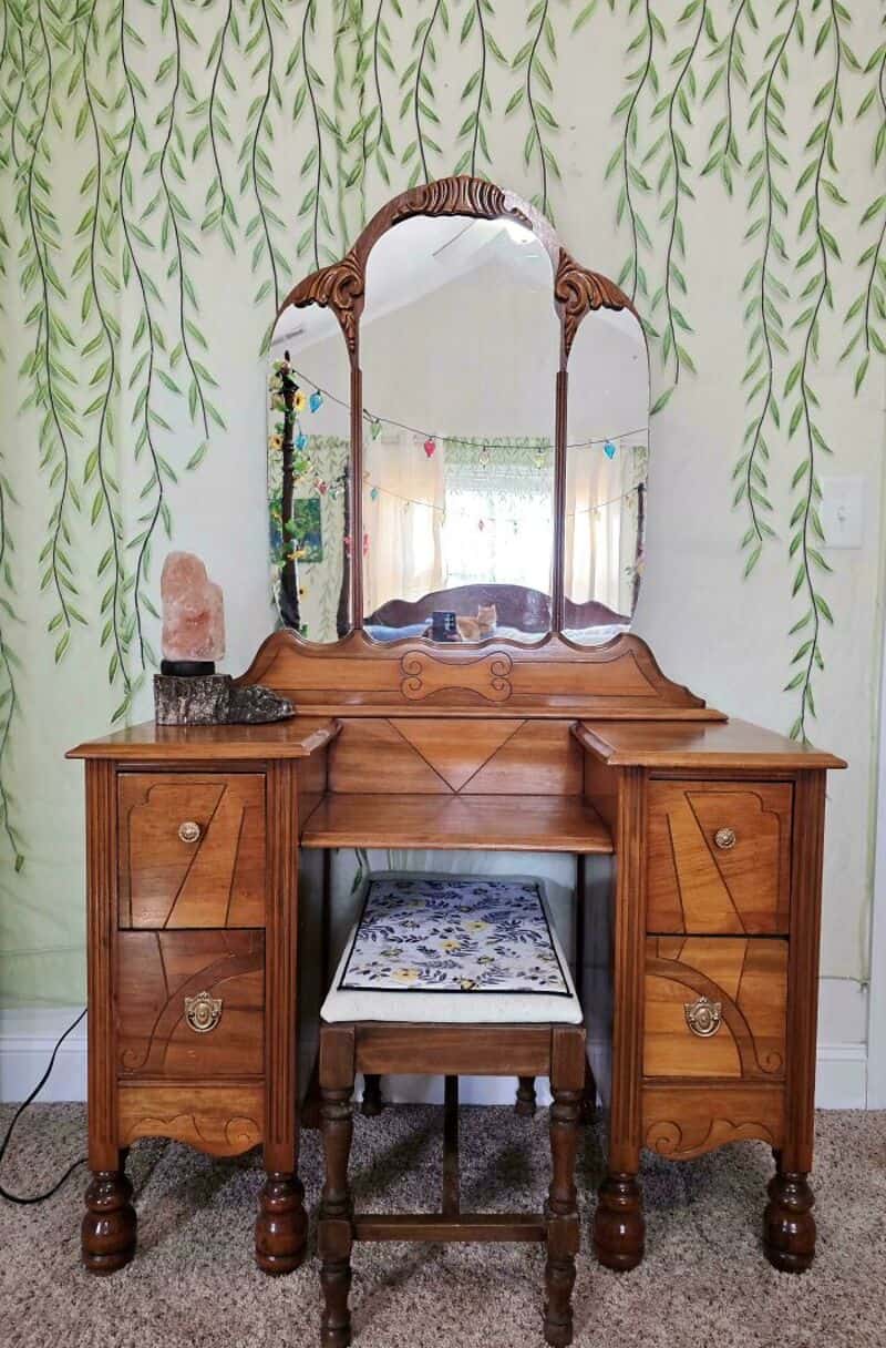 Vintage wooden vanity with mirror, two side drawers, and a cushioned stool.