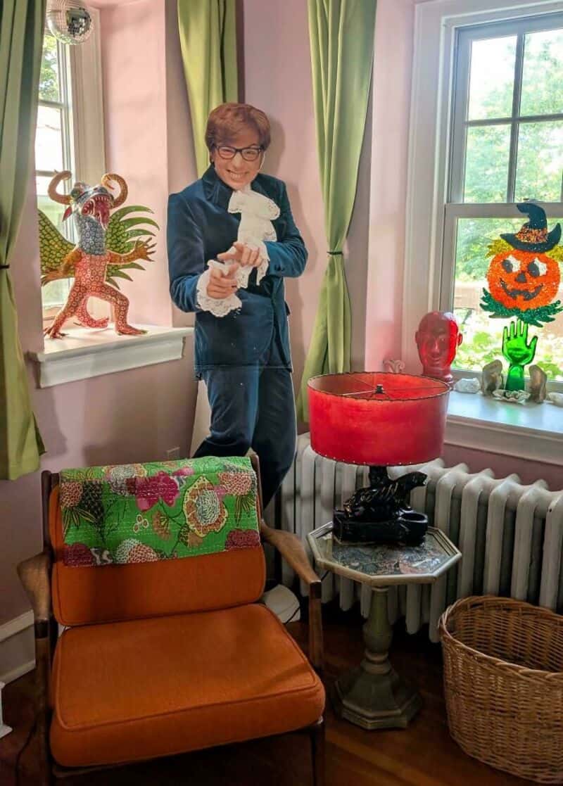 Woman in blue suit holding a white dog figurine in a decorated room.