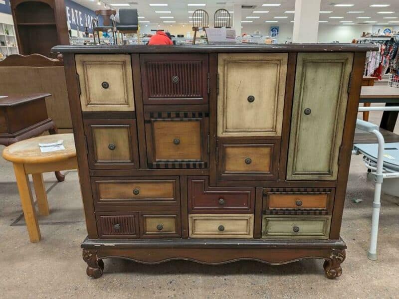 Vintage wooden sideboard with multiple drawers and cabinets at thrift store.