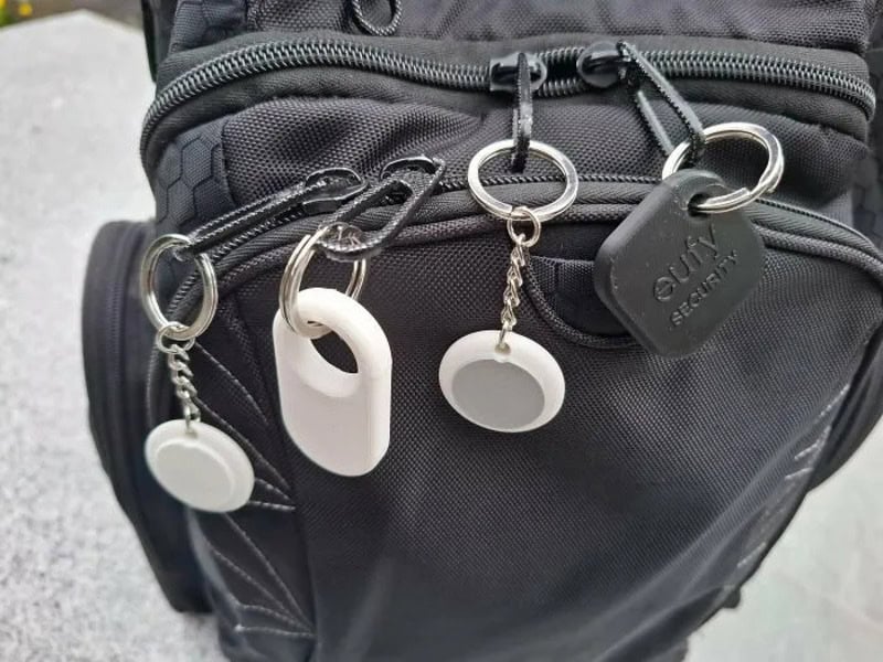 Various keychains and tags attached to a black bag's zipper.