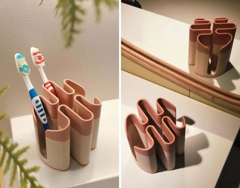 3D printed toothbrush holder with multiple slots, shown with toothbrushes, on a white surface.