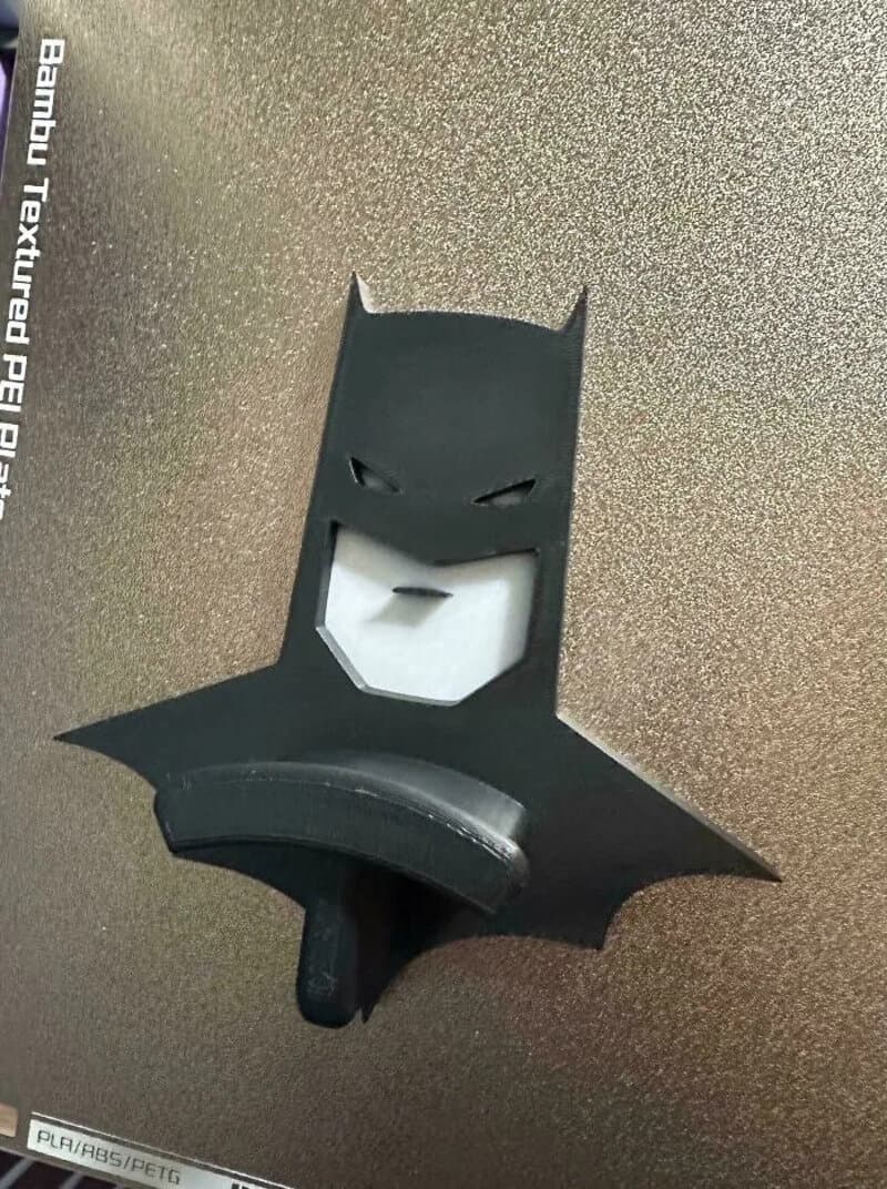 3D printed Batman logo with a face and cape design, black and white colors.
