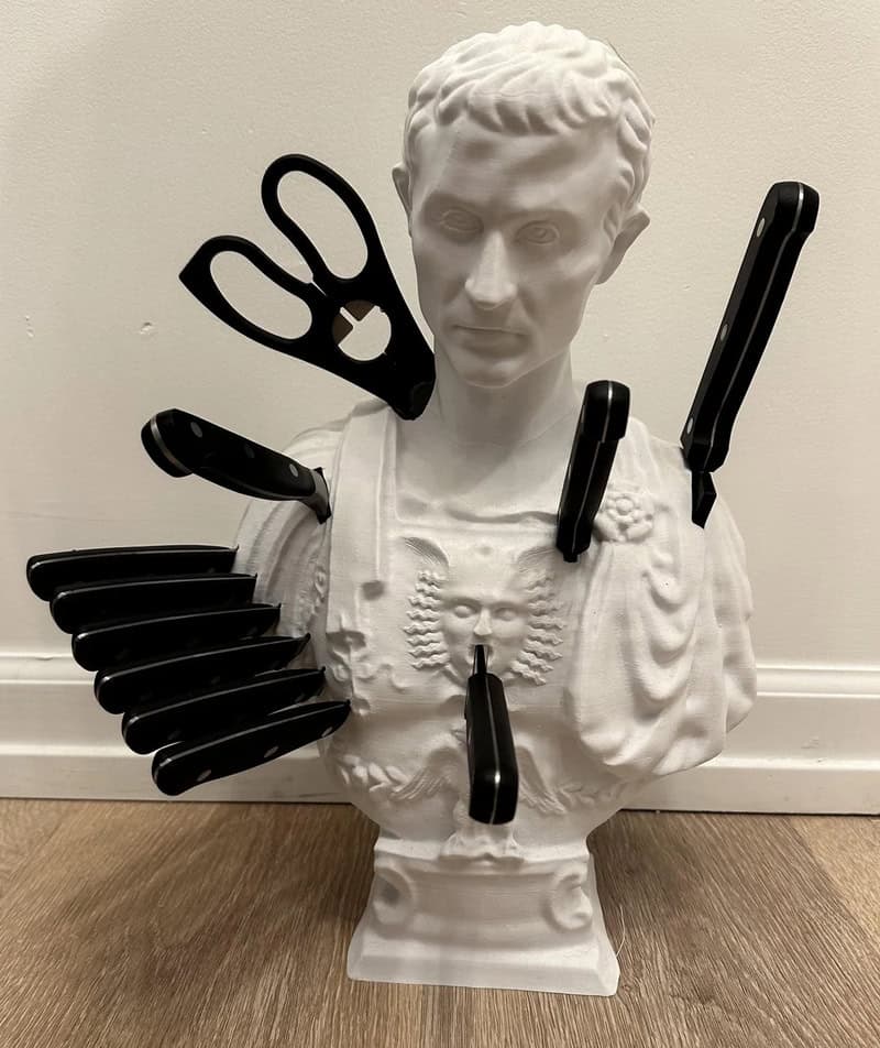 Bust of a classical figure with 3D-printed tools attached, including scissors, knives, and spatulas.