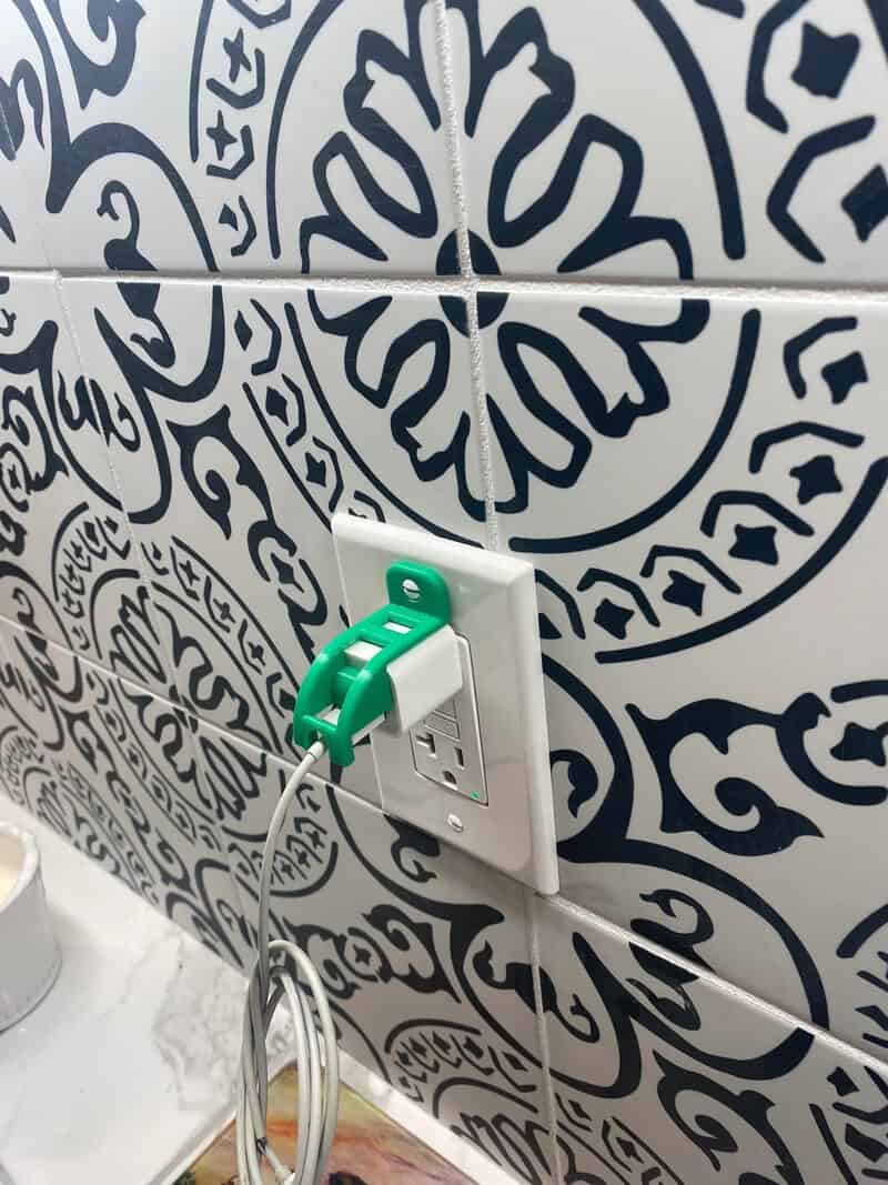 Power strip with green plug in a decorated wall with black and white patterns.