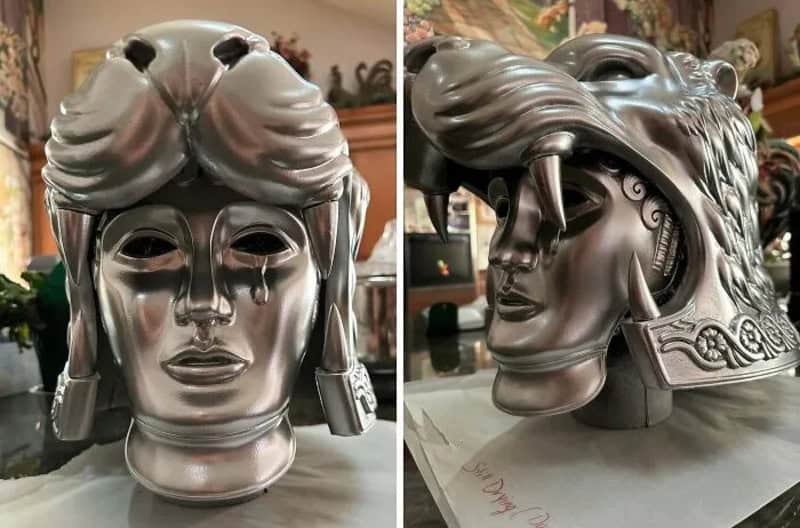 3D printed metallic mask of a woman with elaborate hair and earrings.