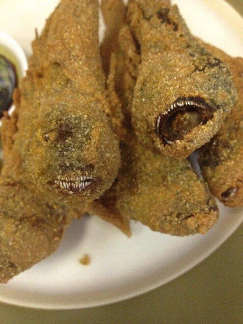 Fried fish with eyes and mouth visible, on a white plate.