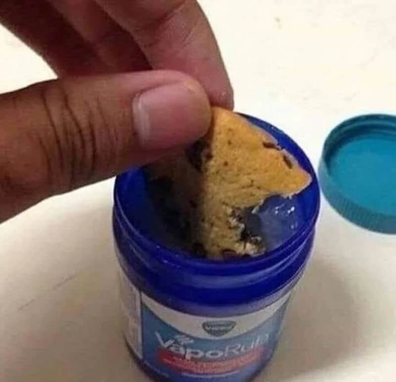 Cookie being dipped into a blue container of Vaseline.